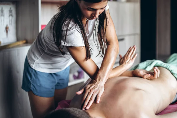 Una fisioterapeuta haciendo masajes de espalda para un hombre en el consultorio médico — Foto de Stock