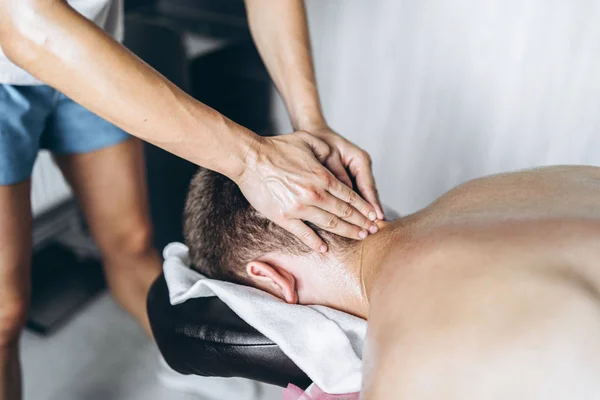 Una fisioterapeuta mujer haciendo masaje de cuello para un hombre en el medi — Foto de Stock