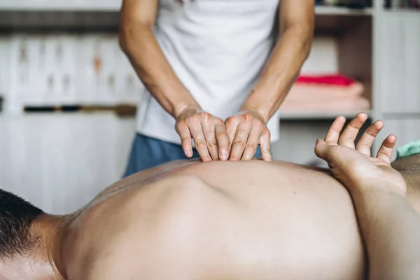 Kvinnlig massös ger tillbaka massage till man som ligger på massag — Stockfoto