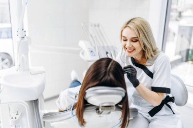 Ofisinde çalışan bir dişçi. Siyah parıltı takan bir kadın doktor.