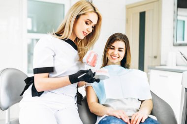 Diş hekimliği. Doktor, dişçi sandalyeye oturan müşteriyi gösteriyor. Dişler, çene.