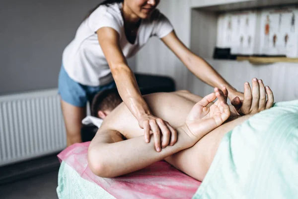 En kvinnlig sjukgymnast gör ryggmassage för en man i medicinen — Stockfoto