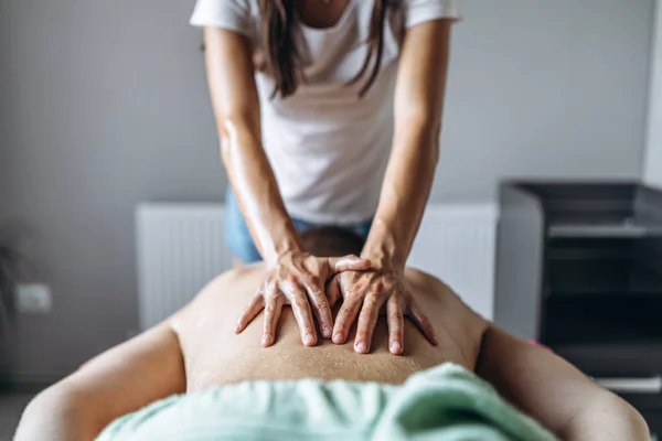 En kvinnlig sjukgymnast gör ryggmassage för en man i medicinen — Stockfoto