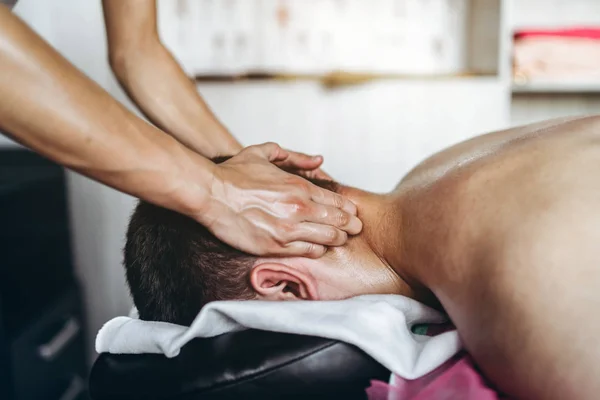 Una fisioterapeuta mujer haciendo masaje de cuello para un hombre en el medi — Foto de Stock