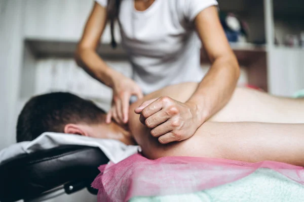 Kvinnlig massös ger tillbaka massage till man som ligger på massag — Stockfoto