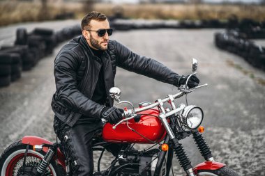 Atlıyla kırmızı motosiklet. Siyah deri ceketli bir adam ve baba.