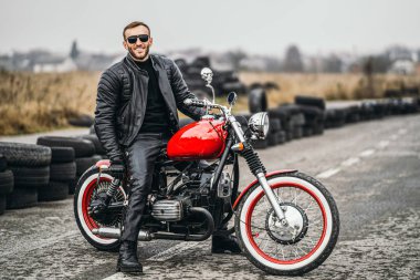 Atlıyla kırmızı motosiklet. Siyah deri ceketli bir adam ve baba.