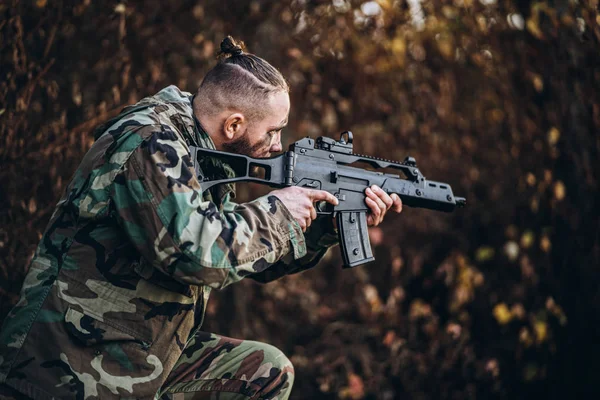 Portret van een camouflage soldaat met geweer en beschilderd gezicht pla — Stockfoto