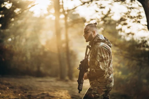 Een camouflage soldaat spelen luchtzacht buiten in het bos, zon — Stockfoto