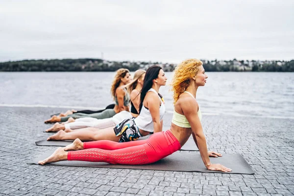 Un grupo de mujeres deportistas están practicando ejercicios de yoga en la esterilla — Foto de Stock