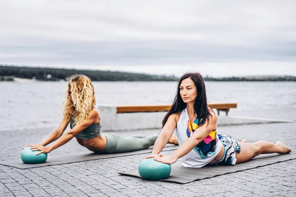 Dos mujeres practican ejercicios de yoga en una esterilla con bolas especiales en — Foto de Stock
