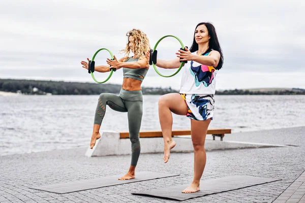 Dos mujeres practican ejercicios de yoga en una esterilla con un deporte especial — Foto de Stock