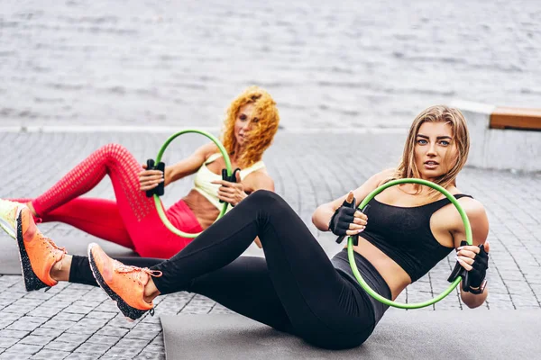 Duas mulheres praticam exercícios de ioga em um tapete na rua perto do th — Fotografia de Stock