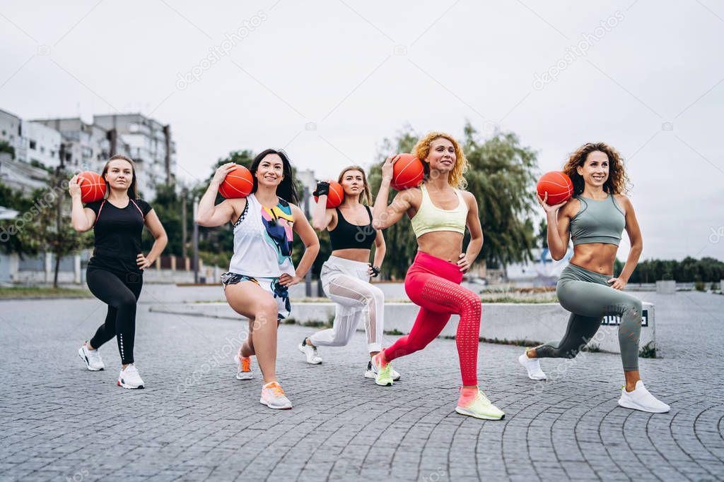 A group of sporty women are posing at camera, performing exercis