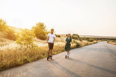 Genç çift tatilde elektrikli scooter sürerken eğleniyor. 