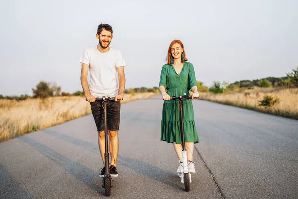 Jong gelukkig glimlachen paar het hebben van plezier rijden elektrische scooter o — Stockfoto