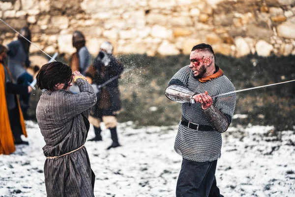 Dois antigos guerreiros de armadura com armas lutando com espadas na neve — Fotografia de Stock