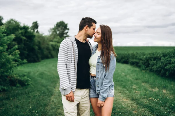 Jovem casal amoroso, mulher e homem, gentilmente abraçando com os olhos fechados no fundo do campo verde. História de amor — Fotografia de Stock