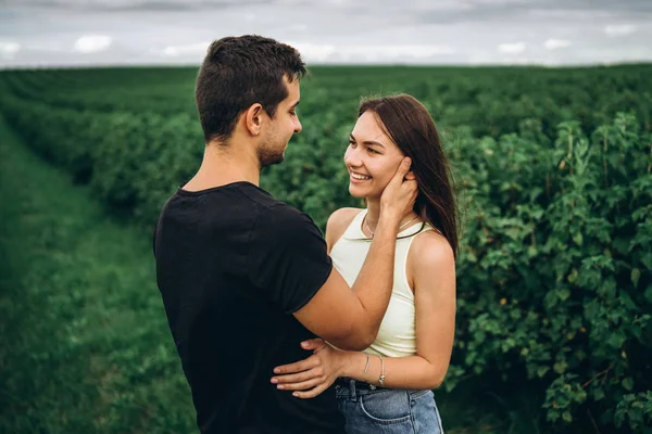Young loving couple gently hugging on the background of green cu — Stock Photo, Image