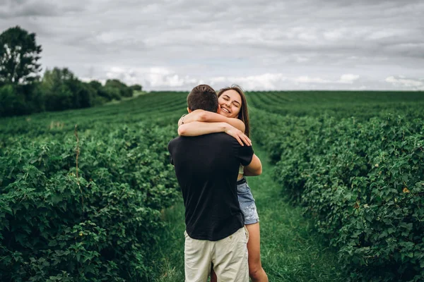 Un couple tendre et aimant marchant dans un champ de groseilles. Homme tourbillonne — Photo