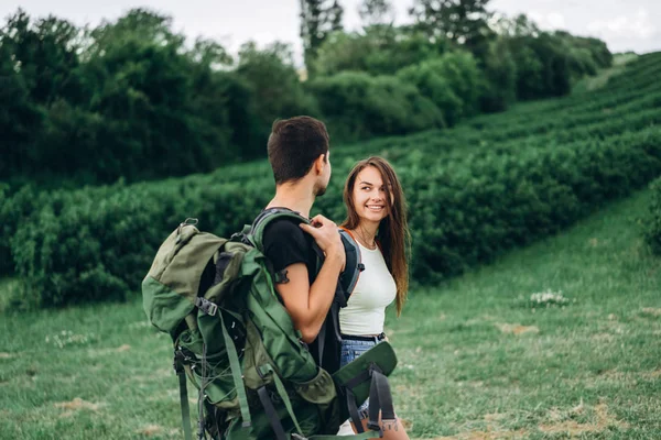 Retrato de jovem casal feliz com mochilas em campo em sp — Fotografia de Stock