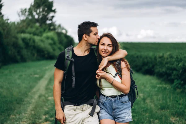 Retrato de jovem casal feliz com mochilas em campo em sp — Fotografia de Stock