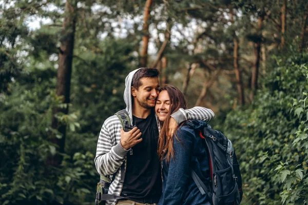 Jovem casal com mochilas nas costas sorrindo e andando i — Fotografia de Stock