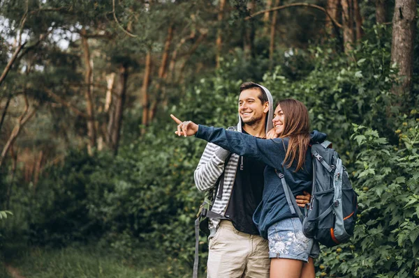 Jong paar met rugzakken op hun rug glimlachen en wandelen i — Stockfoto