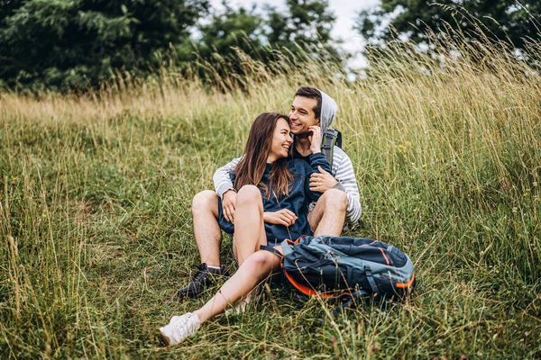 Жінка з довгим волоссям і чоловік сидить на траві в лісі — стокове фото