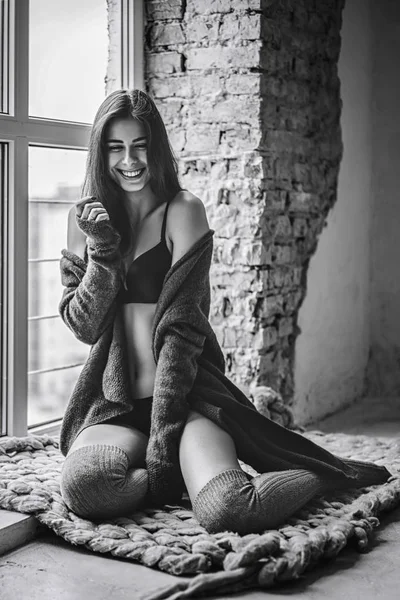 Giovane bruna con viso sorridente in biancheria intima nera, kne lavorato a maglia — Foto Stock