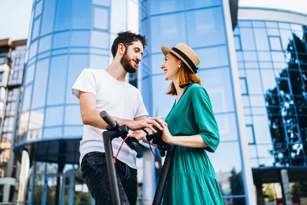 Een jong romantisch paar met elektrische scooters op een date, walkin — Stockfoto