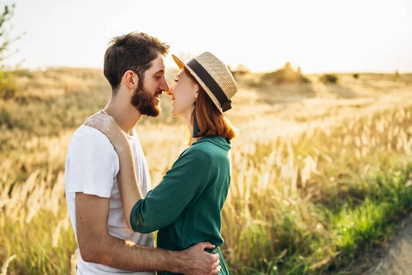 Szczęśliwy młody mężczyzna i kobieta uśmiechający się i przytulający na zewnątrz o zachodzie słońca. Współdziałanie — Zdjęcie stockowe