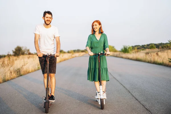 Jong gelukkig glimlachen paar het hebben van plezier rijden elektrische scooter o — Stockfoto