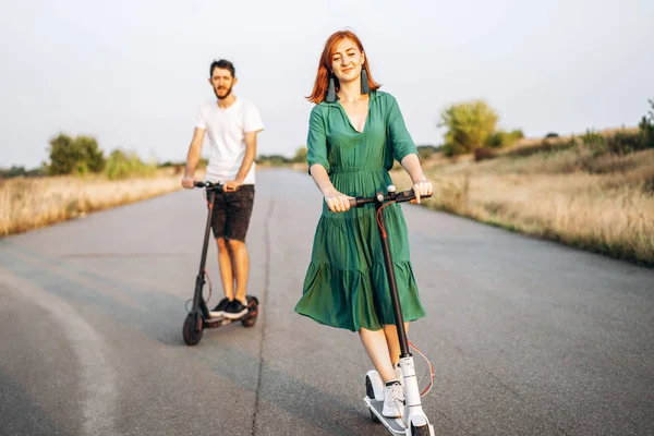 Jong gelukkig glimlachen paar het hebben van plezier rijden elektrische scooter o — Stockfoto