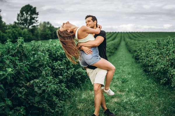 A tender loving couple walking in a field of currant. Man whirls — Stock Photo, Image