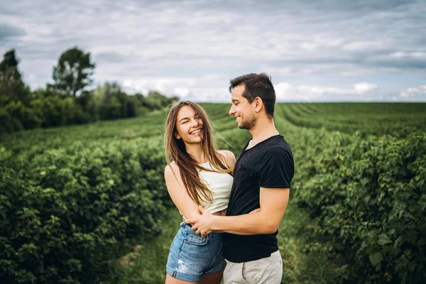 Een teder liefdevol koppel dat in een veld vol bessen loopt. Man wervelt. — Stockfoto