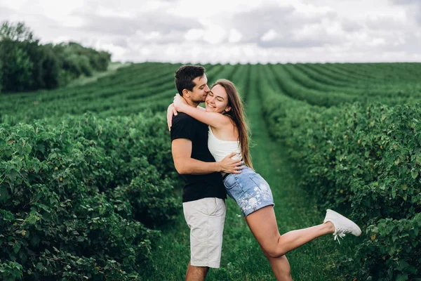 A fiatal szerelmesek gyengéden ölelkeznek a zöld cu hátterén — Stock Fotó