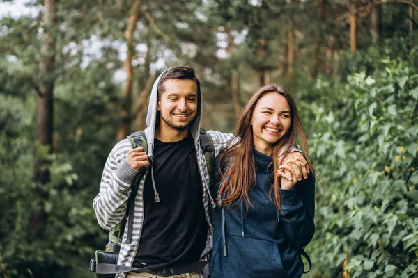 Jong paar met rugzakken op hun rug glimlachen en wandelen i — Stockfoto