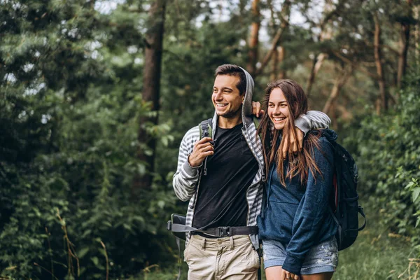 Pareja joven con mochilas en la espalda sonriendo y caminando i — Foto de Stock