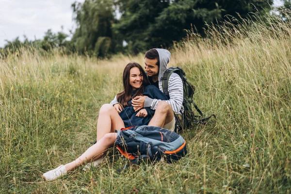 Žena s dlouhými vlasy a muž sedí na trávě v lese — Stock fotografie