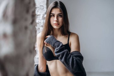 Siyah iç çamaşırlı genç esmer, dizlik ve hırka örüyor.