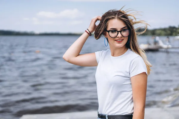 안경을 아름다운 여성의 초상화 티셔츠를 풍경을 배경으로 포즈를 취하는 — 스톡 사진