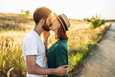Mutlu genç adam ve kadın gün batımında gülüyor ve dışarıda sarılıyor. İnsan kavramı, aşk ve yaşam tarzı.