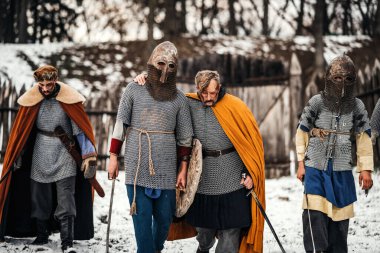 Kasklı ve cüppeli cesur şövalyeler ellerinde silahlarla savaştan sonra geri dönüyorlar. Savaş ve tarih kavramı.