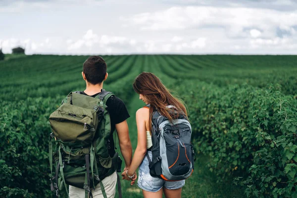 看到一对年轻夫妇背着背包在醋栗种植园手牵着手 在一起度过时光 旅游概念 — 图库照片