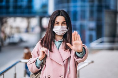 Dışarıdaki tıbbi maskeli kadın virüs enfeksiyonunu önlemek için sosyal güvenlik mesafesi için elinde dur işareti olduğunu gösteriyor. Coronavirus, COVID-19, virüs, salgın, salgın, salgın, karantina konsepti