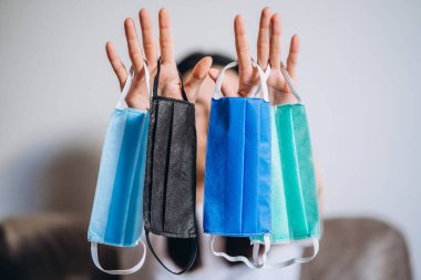 Karantina zamanında evde bulunan kadın virüs hastalıklarını, COVID-19 'u, salgın hastalıkları ve salgın hastalıkları önlemek için renkli koruyucu maskeler taşıyor.