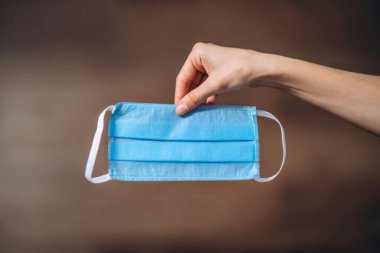 Karantina zamanındaki kadın elleri virüs hastalıklarını, COVID-19 'u, salgın hastalıkları ve salgın hastalıkları önlemek için koruyucu tıbbi maske tutuyor.