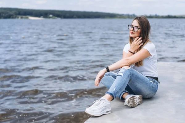 Mujer Joven Con Pelo Largo Gafas Elegantes Posando Orilla Hormigón —  Fotos de Stock