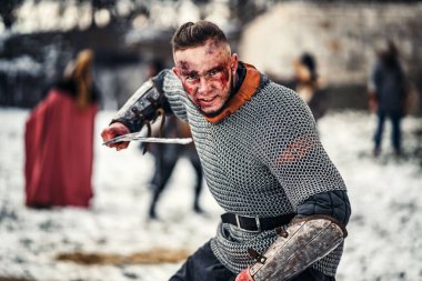 Kılıçla savaşa giden genç bir savaşçının şeytani duyguları. Arka planda, kış mevsiminde kalenin yanında savaş.